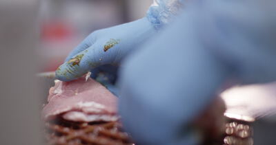 Marinierte Fleischscheiben werden von Hand zu einem großen Spieß geschichtet