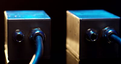 Metallgehäuse mit Kabelverschraubungen und blauen Anschlusskabeln
