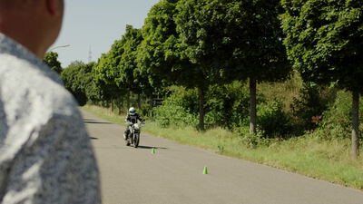 Motorradfahrer übt auf einer baumgesäumten Straße mit Pylonen Motorradfahrer übt auf einer baumgesäumten Straße mit Pylonen, Fahrsicherheitstraining, Motorradtraining und Allee als 4K