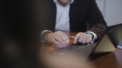 Geschäftsmann arbeitet am Laptop und hält einen Stift am Schreibtisch