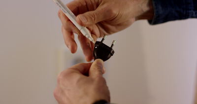 Hände halten einen schwarzen Netzstecker mit weißem Kabel Hände halten einen schwarzen Netzstecker mit weißem Kabel, Netzstecker Nahaufnahme, Stromstecker in der Hand und