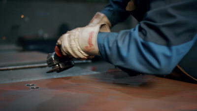 Arbeiter bearbeitet eine Metallplatte mit einem Winkelschleifer