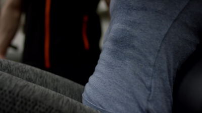 Person in grauer Sportkleidung trainiert an einem Fitnessgerät im Studio