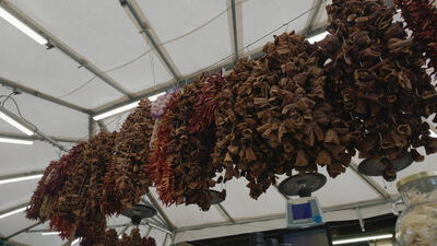Getrocknete Paprika und Chiliketten am Marktstand: getrocknete Paprika am Marktstand, Chiliketten hängen von der Decke