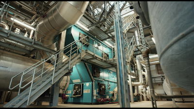 Weite Innenansicht einer Industrieanlage mit Stahltreppe und teal Maschine