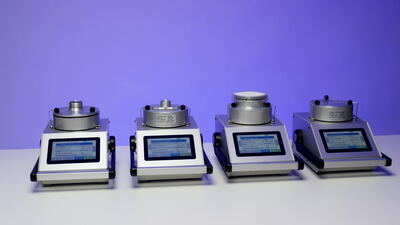 Vier Labormessgeräte mit Touchscreen vor violettem Hintergrund