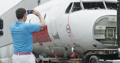 Mann fotografiert einen Flugzeugrumpf mit dem Smartphone