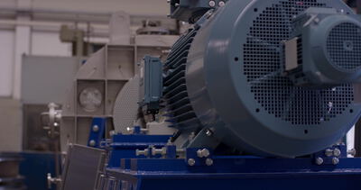 Großer Elektromotor mit Kühlrippen auf blauer Grundplatte in der Fertigung