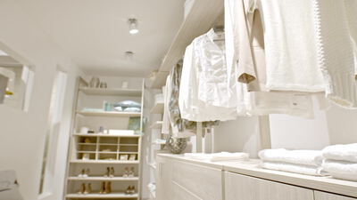 Heller begehbarer Kleiderschrank mit weißer Kleidung und Regalen