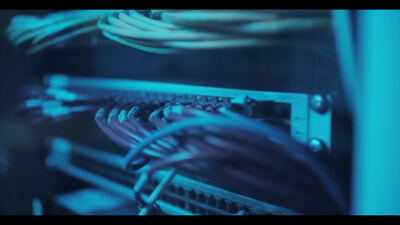 Netzwerk Switch mit eingesteckten Kabeln im blau beleuchteten Serverrack