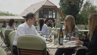 Menschen sitzen beim Essen auf einer Terrasse im Freien