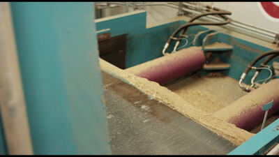 Industriemaschine mit roter Walze verarbeitet helles Material