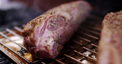 Gewürzter roher Schweinebraten liegt auf heißem Grillrost: gewürzter Schweinebraten, gewürztes Fleisch