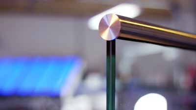 Ecke einer Verbundglasscheibe mit Metallbeschlag in Nahaufnahme, Verbundglas Ecke, Glaspaneel und Metallhandlauf als 4K