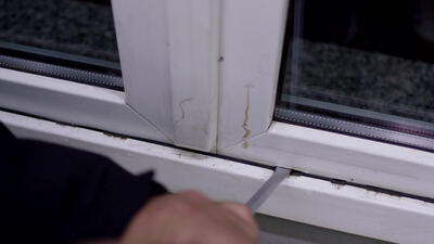 Hand bearbeitet ein Kunststofffenster mit einem Werkzeug
