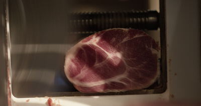 Marmoriertes Fleisch liegt im Schacht der Aufschnittmaschine