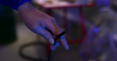 Hand hält ein beleuchtetes Inspektionswerkzeug mit Kabel in der Werkstatt