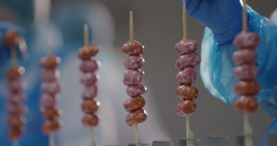 Rohe Wurstspieße stehen aufgereiht in der Metzgerei bereit