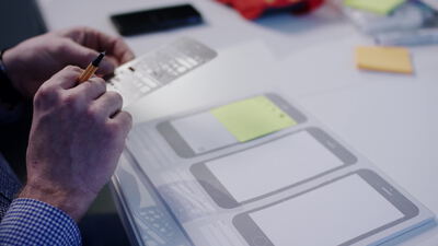 Hände zeichnen App Wireframes mit einer Schablone auf Papier
