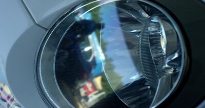 Nahaufnahme eines Autoscheinwerfers mit verchromtem Reflektor und Streuscheibe