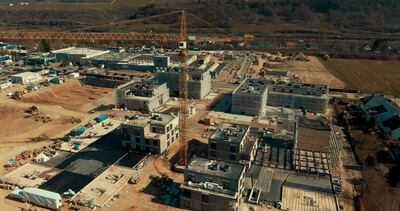 Wohnbaustelle mit Turmkran und mehreren Rohbauten aus der Luft