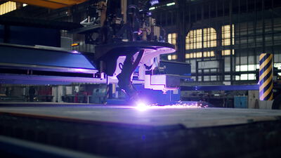 Plasmaschneidanlage schneidet eine Stahlplatte in der Fabrikhalle, Plasmaschneiden, Metallschnitt und Schneidfunken als 4K