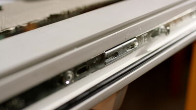 Nahaufnahme eines Fensterbeschlags am weißen Fensterrahmen