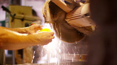 Handwerker schleift ein Werkstück an der Schleifscheibe