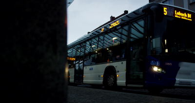 Beleuchteter Stadtbus am Abend an einer Haltestelle