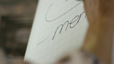 Hand schreibt mit einem Stift Wörter auf ein Flipchart