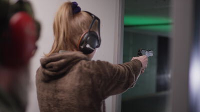 Frau zielt mit einer Pistole auf dem Indoor Schießstand