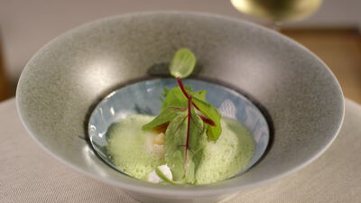 Goldener Löffel über der grünen Schaumsuppe in der Schale