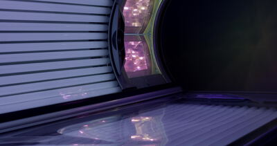 Moderne Sonnenbank mit blau lila Röhren und Lichtpaneel im Solarium