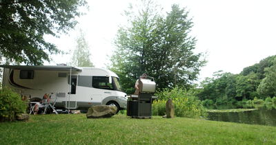 Wohnmobil steht auf einer Wiese am See