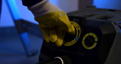 Behandschuhte Hand stellt einen Drehregler an einer Reinigungsmaschine ein