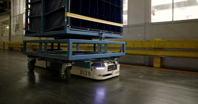 Fahrerloser Transportroboter fährt durch einen hellen Fabrikgang