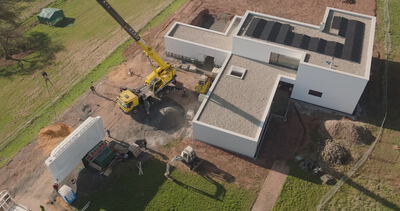Senkrechte Luftaufnahme eines modernen Flachdachhauses im Bau mit Kran