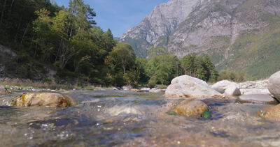 Gebirgsfluss aus Froschperspektive mit Felsen und hoher Bergflanke
