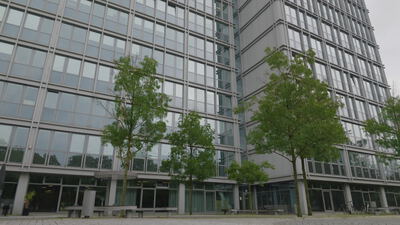 Glasbürogebäude erhebt sich über einem begrünten Innenhof mit Bäumen: Glasbürogebäude, modernes Bürogebäude