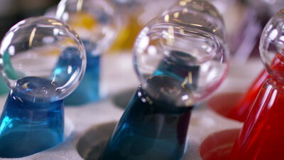 Laborgläser mit farbigen Flüssigkeiten in Blau und Rot