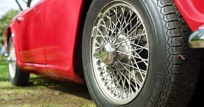 Verchromtes Speichenrad eines roten Oldtimer Sportwagens