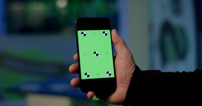 Hand hält Smartphone mit grünem Trackingbildschirm