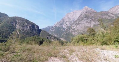 Felsmassiv ragt über trockene Wiese im sonnigen Gebirgstal