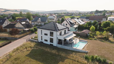 Luftaufnahme eines modernen Einfamilienhauses mit Pool im Wohngebiet