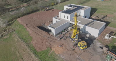 Drohne umkreist modernes Haus mit Kran auf Baustelle