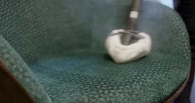 Dampfdüse dringt in Nahaufnahme tief in grünen Polsterstoff ein