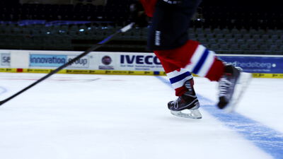 Schlittschuhe eines Eishockeyspielers gleiten übers Eis
