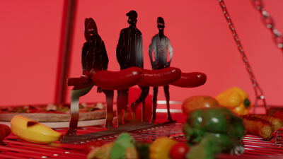 Rote Food Art Szene mit gegrillter Wurst und kleinen Modellfiguren
