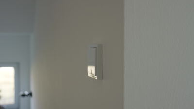 Moderne Wandleuchte leuchtet warm an einer weißen Wand
