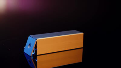 Ein blau und kupferfarbener Metallblock dreht sich im Studiolicht
